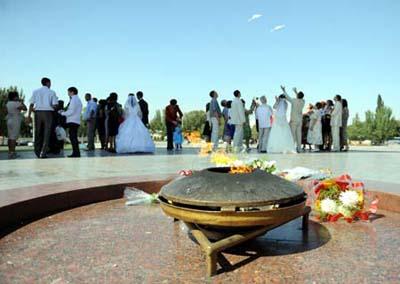 The eternal flame is seen with the background of a newly-married couple setting free doves at the Victory Square in Bishkek, capital of Kyrgyzstan, Sept. 12, 2009. It is a tradition for many Kyrgyzstan's newly-married couples to come to the Victory Square to pray for happiness in their life.(Xinhua/Sadat)